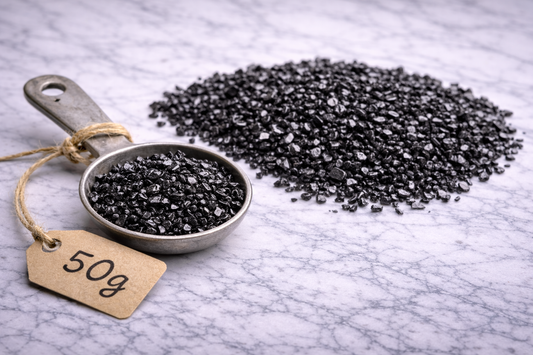 “Fine crushed elite shungite on marble surface with metal spoon labeled 50g”