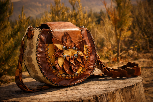 Handcrafted one-of-a-kind leather crossbody bag made from recycled leather, featuring layered leaf detailing and metal accents, photographed on weathered wood in natural light, honouring earth-made materials and slow, intentional craftsmanship.