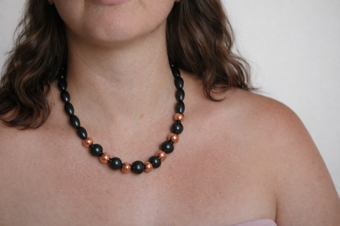 Shungite and copper bead necklace worn on model against a soft neutral background with natural lighting