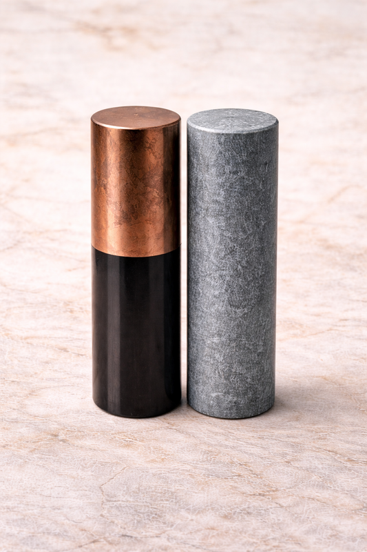 Shungite and soapstone meditation cylinders displayed on marble surface, crystal harmonizers for energy balancing and spiritual practice