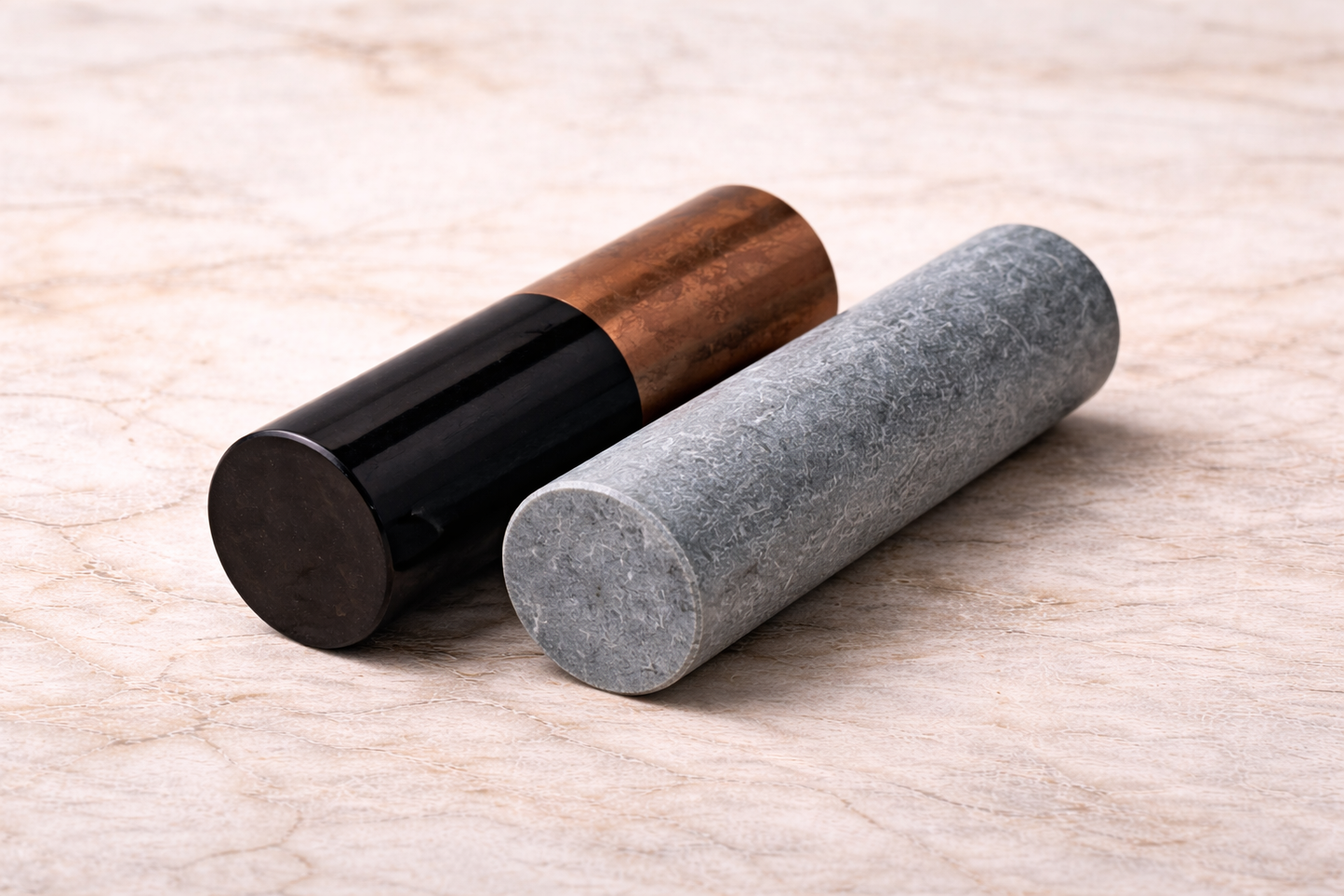 Shungite and soapstone meditation cylinders displayed on marble surface, crystal harmonizers for energy balancing and spiritual practice