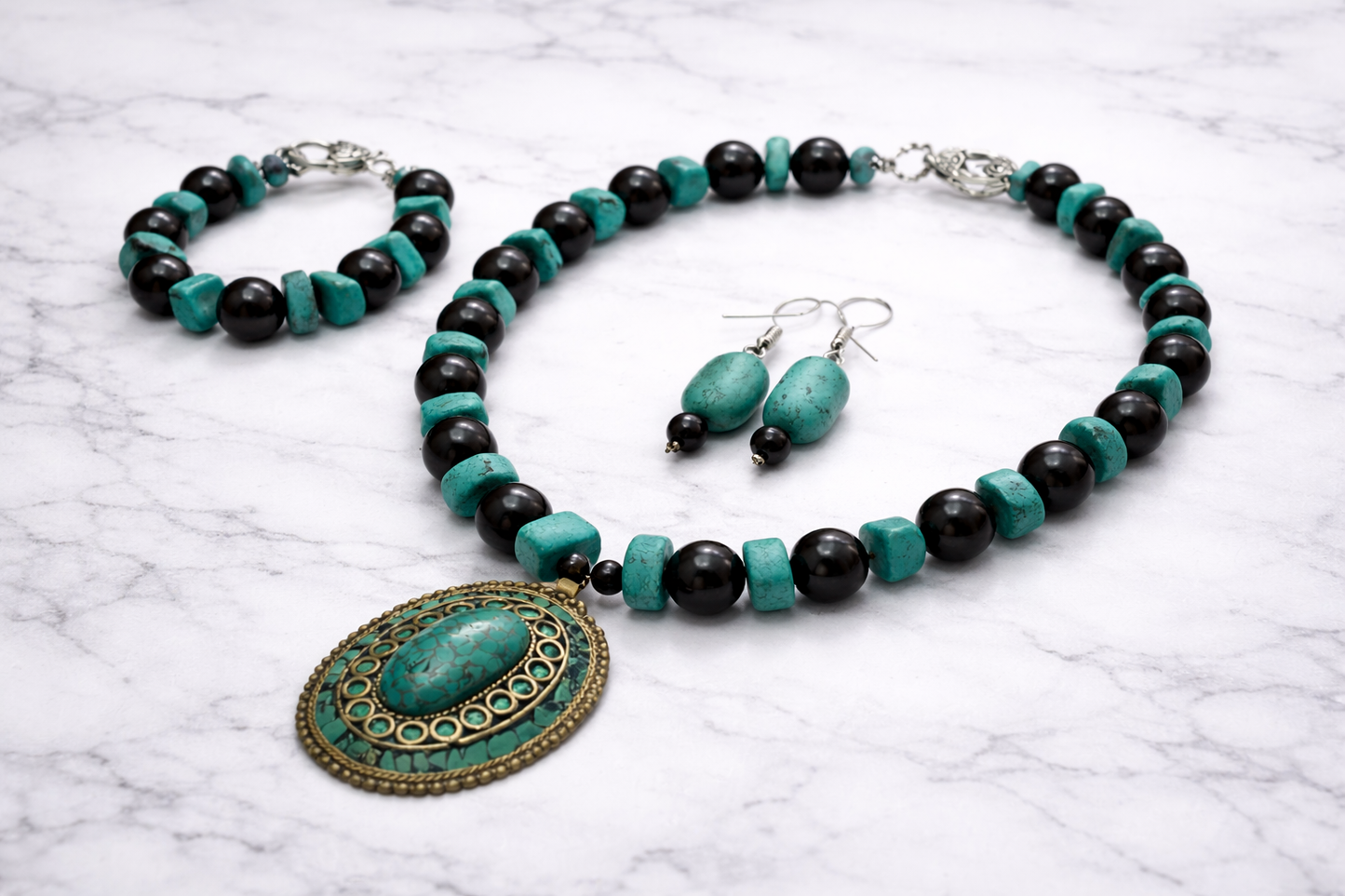 Handmade shungite and turquoise jewelry set with necklace, bracelet and earrings on marble background