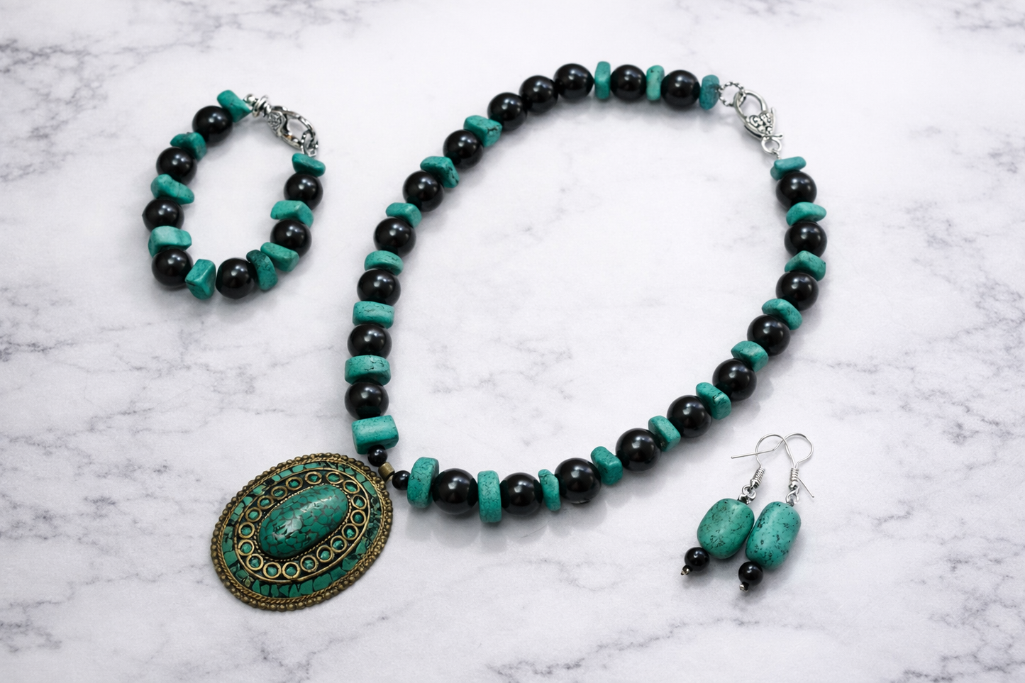 Handmade shungite and turquoise jewelry set with necklace, bracelet and earrings on marble background