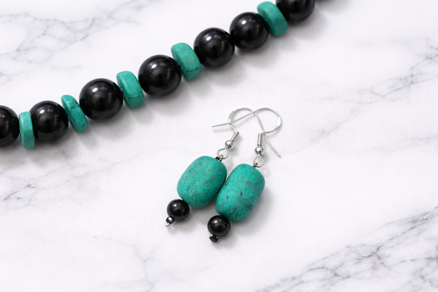 Handmade shungite and turquoise earrings with matching bracelet on white marble background